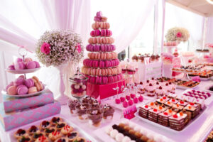 A table of catered desserts, including macarons stacked in a tree formation.